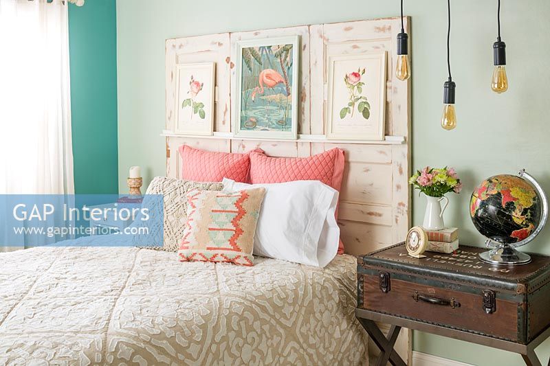 Distressed wooden headboard with paintings in eclectic bedroom 