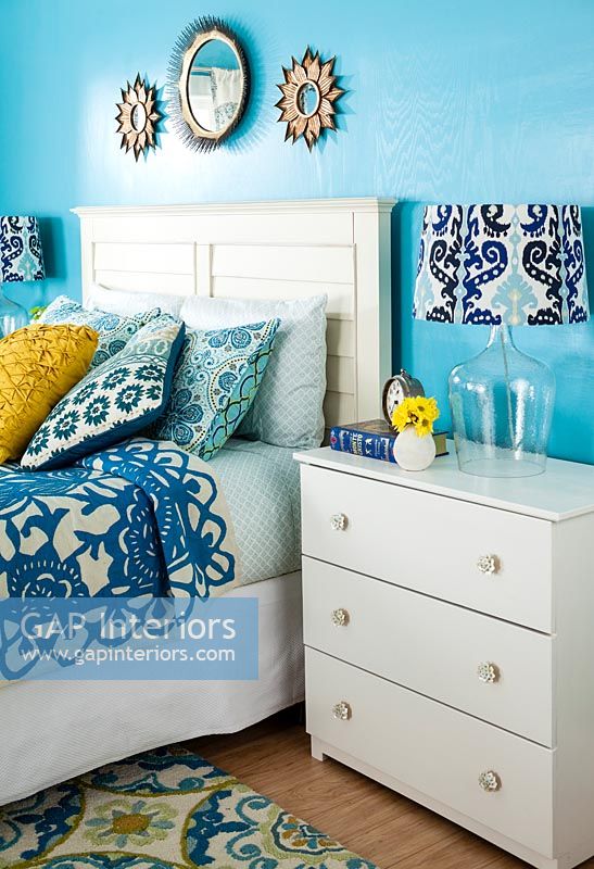 Blue bedroom with white furniture and patterned accessories 