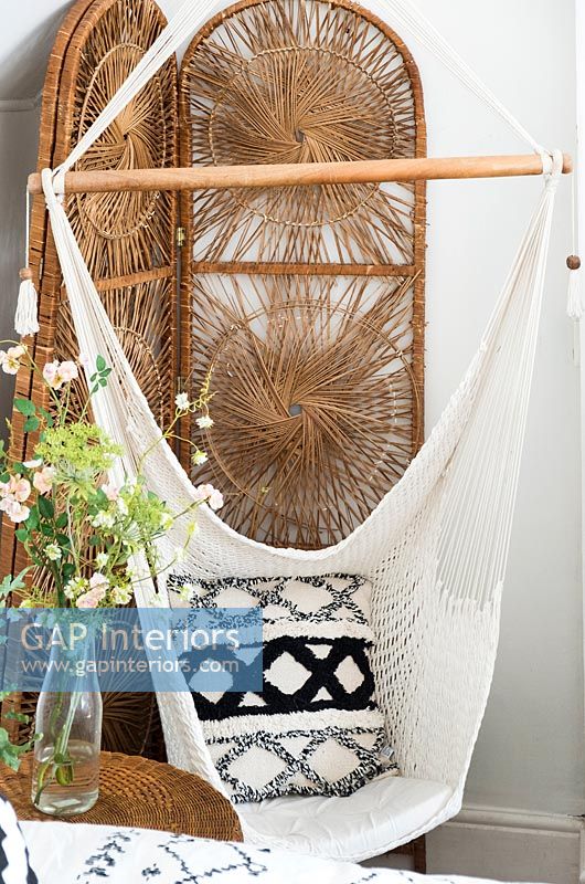 Macrame swing seat and wicker screen in country bedroom 