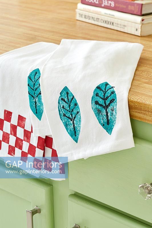 Tea towels with stamped designs on kitchen worktop 