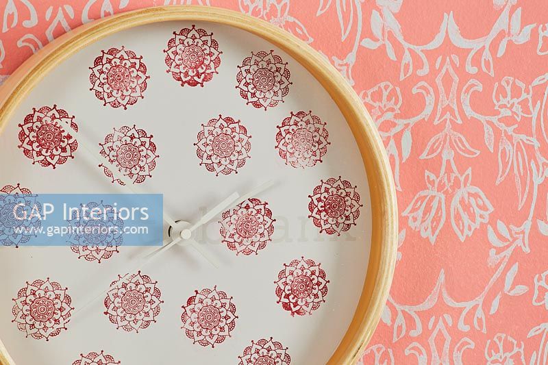 Decorative wall clock and colourful orange patterned wallpaper 