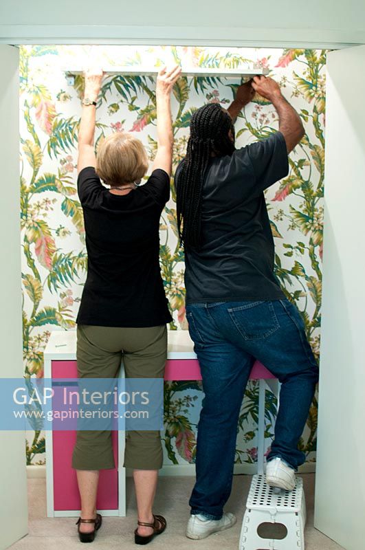 People wallpapering with tropical print wallpaper 