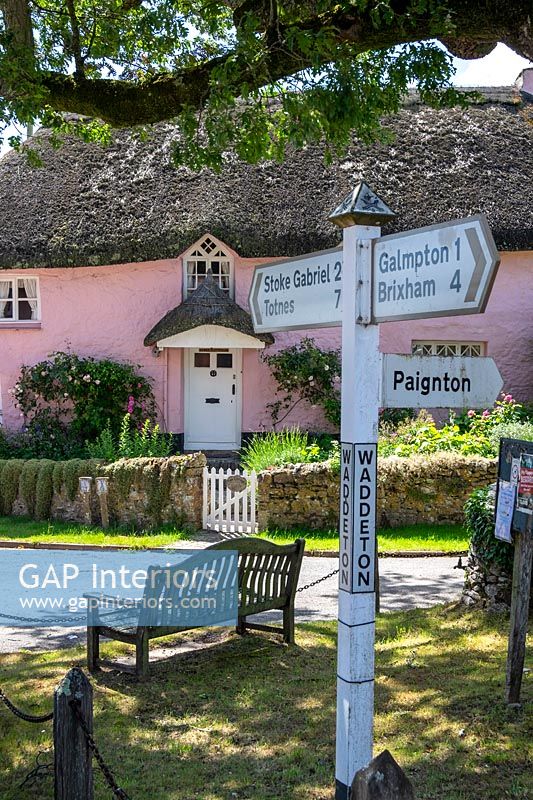 Pretty pink painted cottage with street signs 