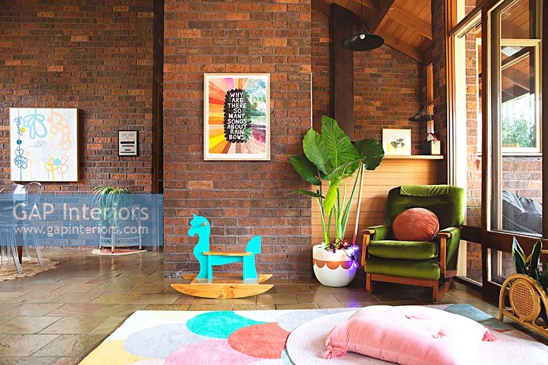 Toys in large modern living room with exposed brick walls and stone flooring 