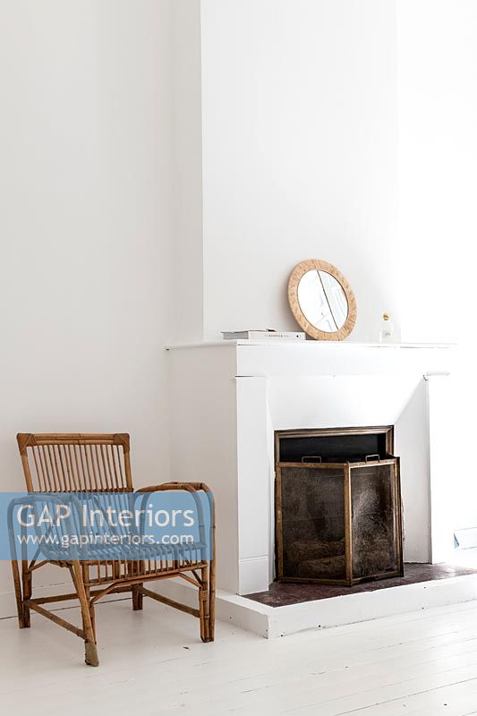 White painted fireplace with wicker chair 