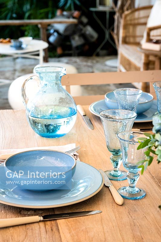 Detail of blue crockery and glassware on outdoor dining table 