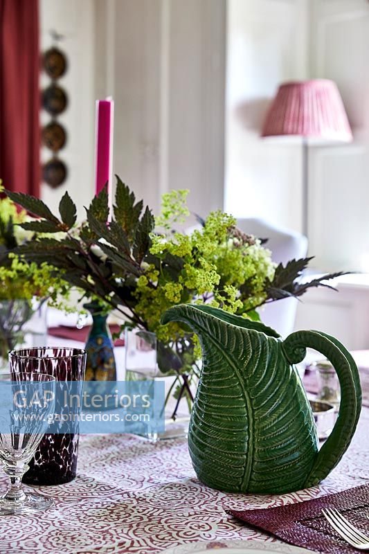Green jug and flowers on country dining table 