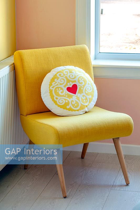Heart patterned cushion on modern yellow chair 