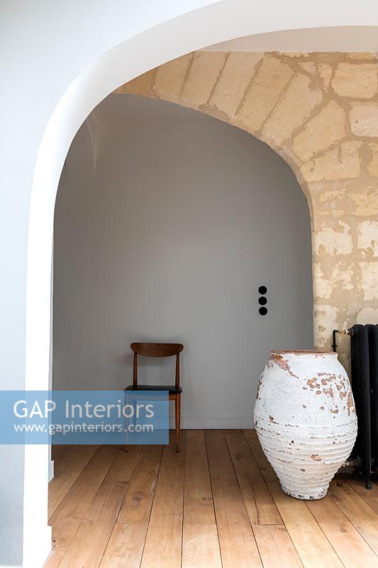 Large painted empty urn in hallway with exposed stone wall 