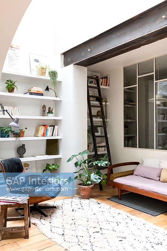 Small modern reading room with ladder next to bookshelves 