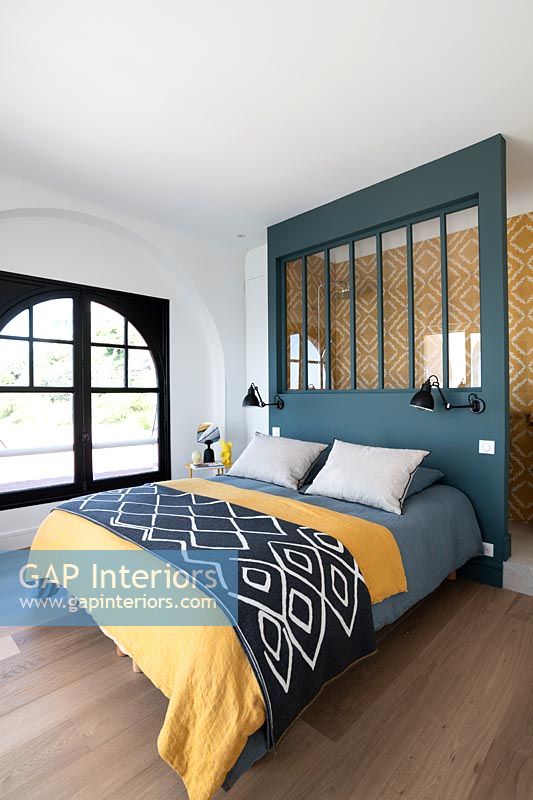 Colourful modern bedroom with headboard divider to en-suite bathroom area 