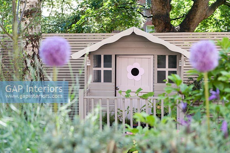 Pink painted playhouse in modern garden 