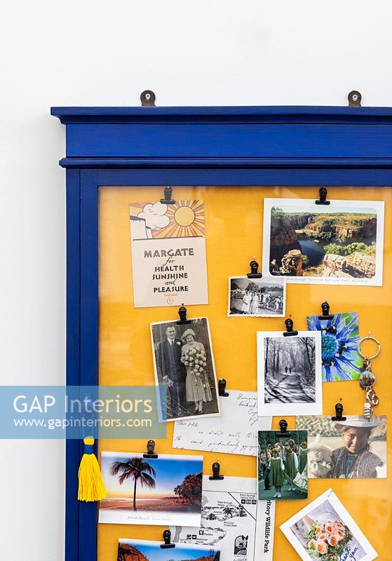 Blue and yellow framed notice board on wall 