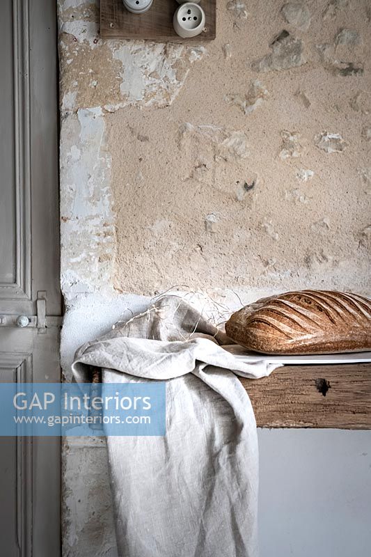 Detail of loaf of bread on rustic table next to textured wall