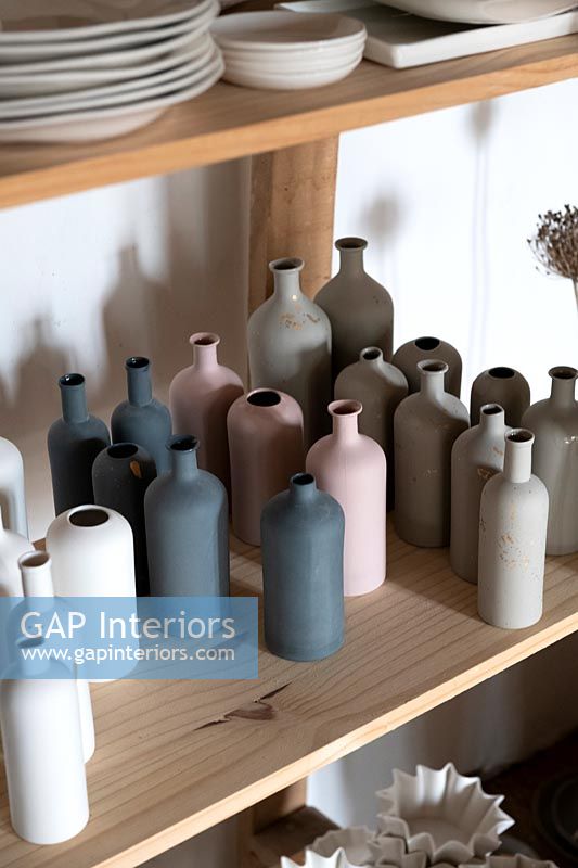 Collection of ceramic bottles in muted tones on shelf 
