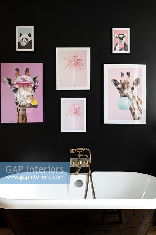 Colourful pictures on black wall above bath in modern bathroom 