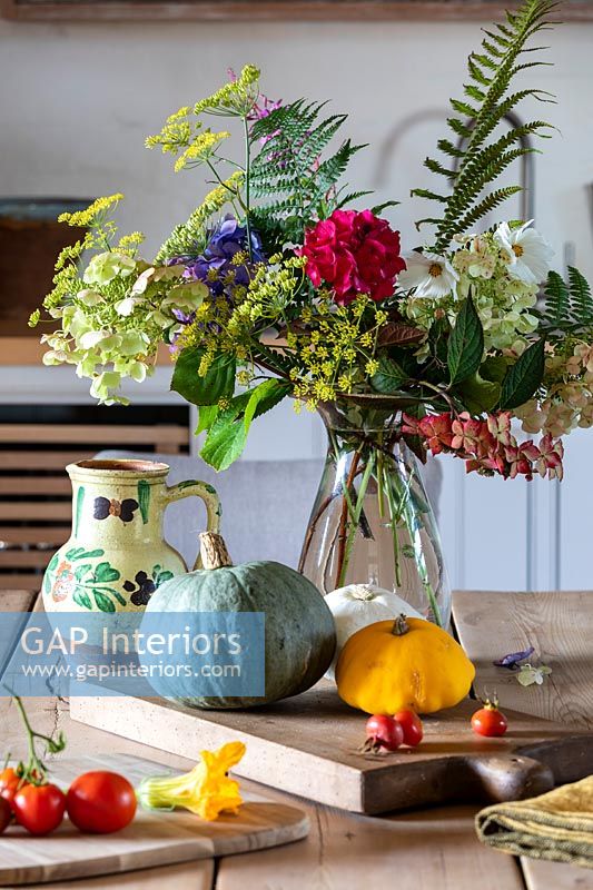 Detail of flower arrangement on country table with harvested vegetables 