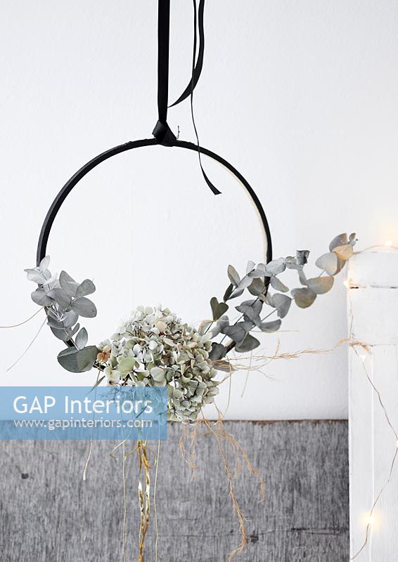 Silver grey foliage displayed on a hanging black hoop with fairy lights 