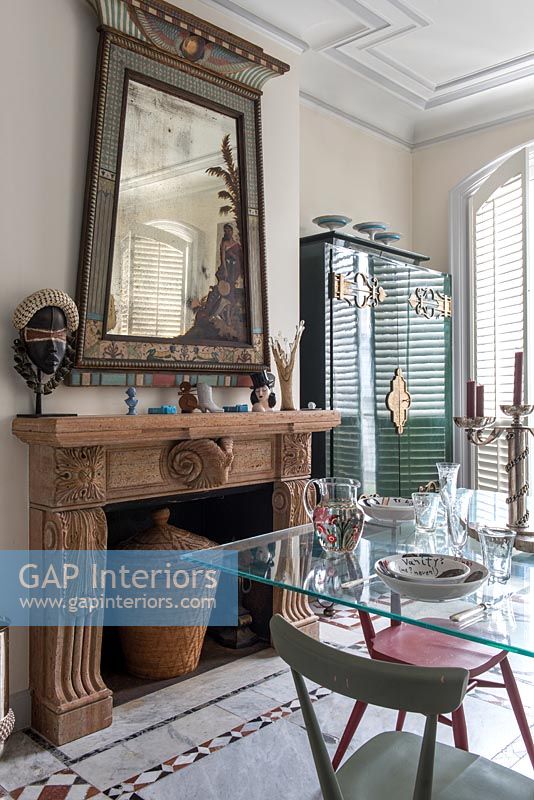 Carved wooden mantelpiece and large unusual mirror in eclectic dining room 