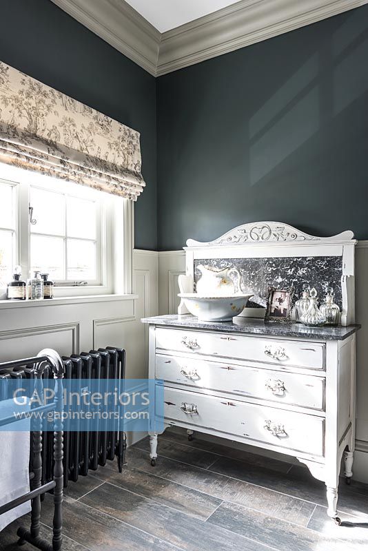 Distressed white painted chest of drawers with sink in modern bathroom 