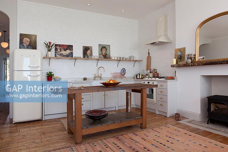 Simple wooden island in white modern kitchen with retro appliances 