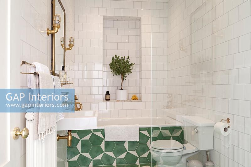 Green and white patterned tiling on side of bath in modern bathroom 