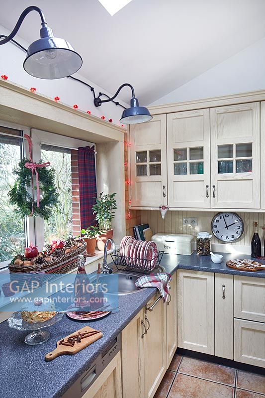 Fairy lights around country kitchen window with Christmas decorations 