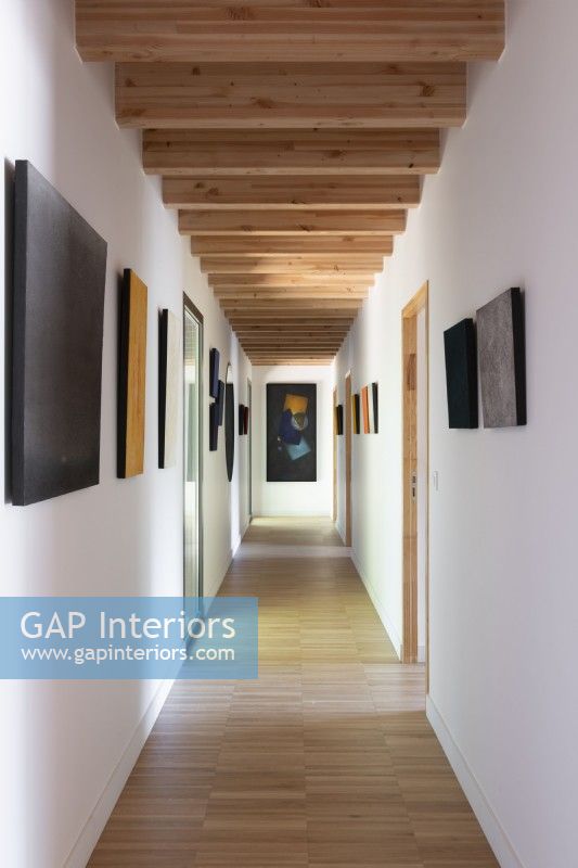 View along narrow modern corridor with artwork on walls