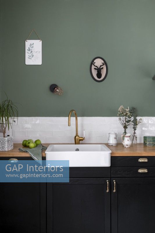 Butler sink in green and black kitchen