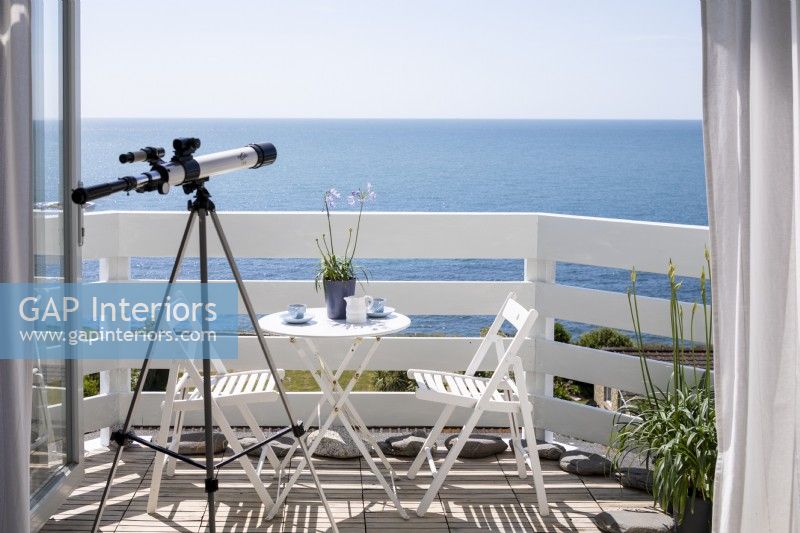 Telescope looking out across the sea, white painted balcony.