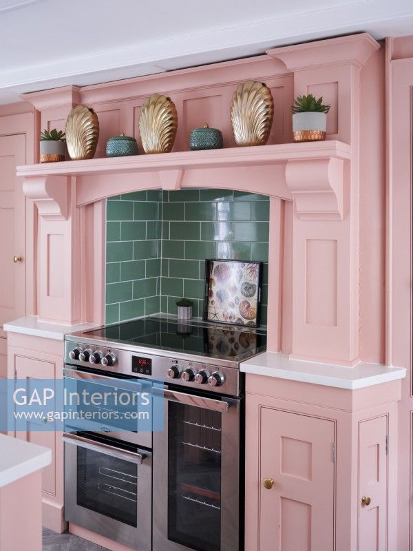 handmade kitchen with painted pink units with stainless steel cooker