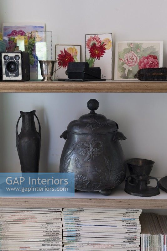 Decorative pewter items on shelves, floral paintings