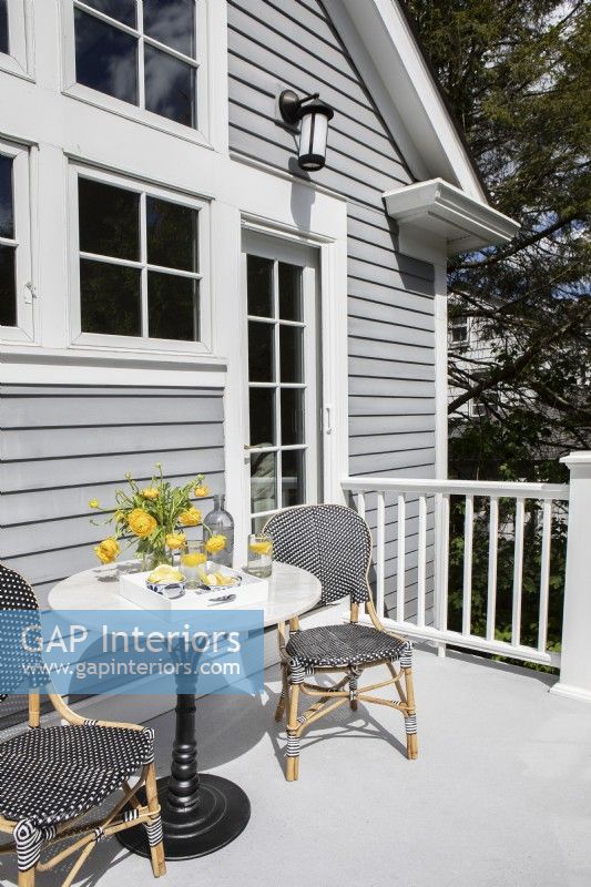 Porch seating with small round table and two wicker chairs.