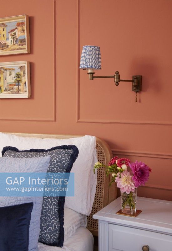 Bedroom detail with terracotta panelling, textured blue cushions and wall mounted vintage lights.