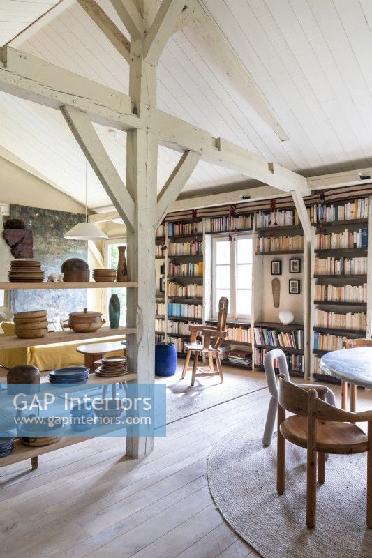 Exposed beams and shelves of ceramics in country reading room
