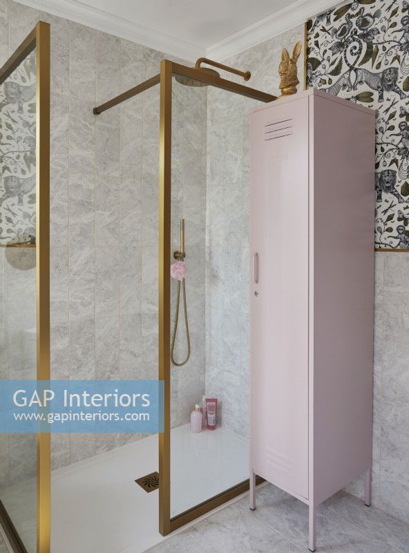 Bathroom with patterned wallpaper, gold frame shower cubicle and a pink storage locker.