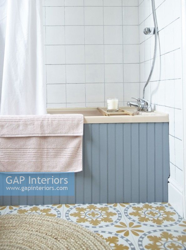 Bathroom detail showing blue panelled bath and retro looking flooring.