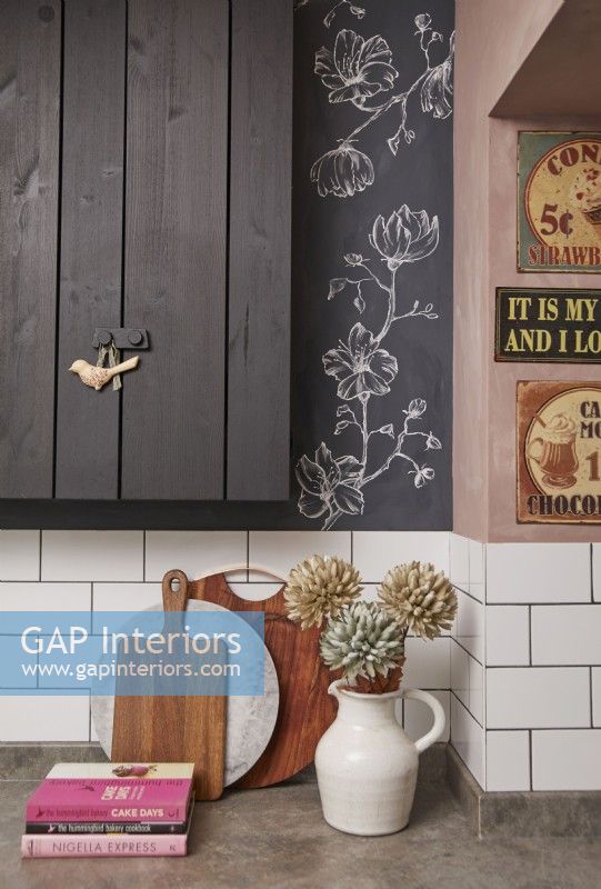 Kitchen details with black painted cupboards, floral artwork and vintage signs.
