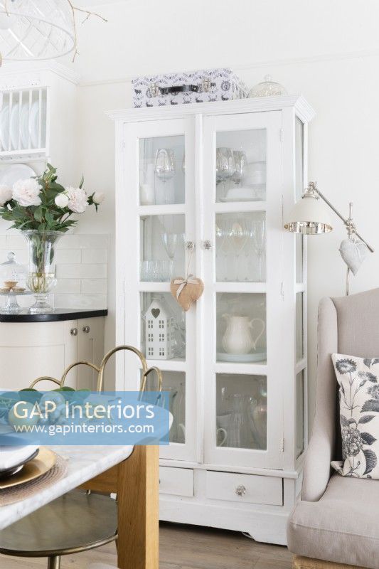 Tall reclaimed white hand painted cabinet with glass panelled doors in an open plan kitchen diner