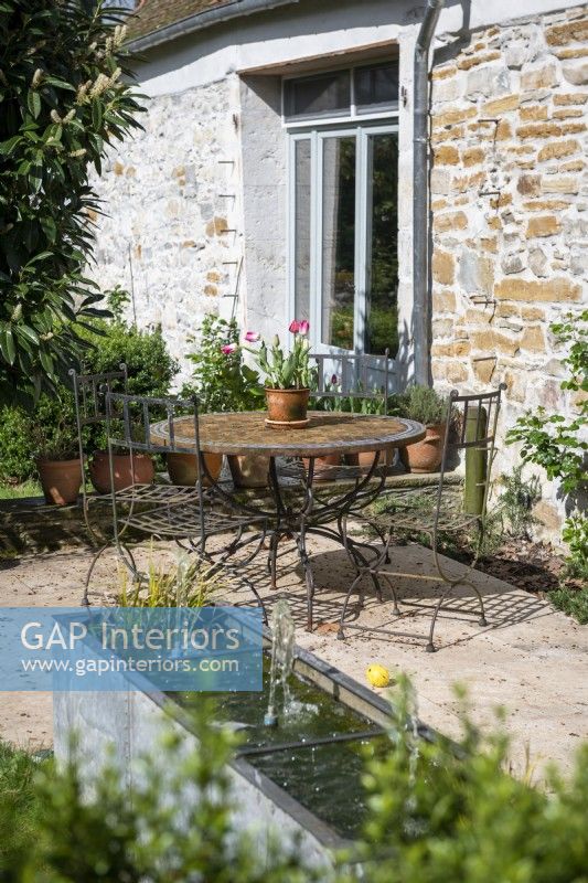 Rusting metal bistro table and chairs on terrace of country home