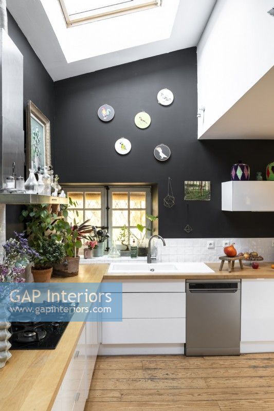 Modern kitchen with black painted walls and white units 