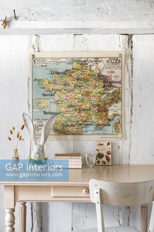 Wall mounted map above pale pink desk in country study