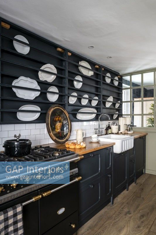 Black painted modern country kitchen with display of white plates