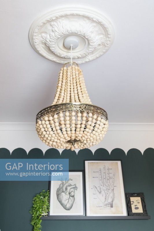 Handmade beaded chandelier hanging from a white ceiling in a green scalloped painted room