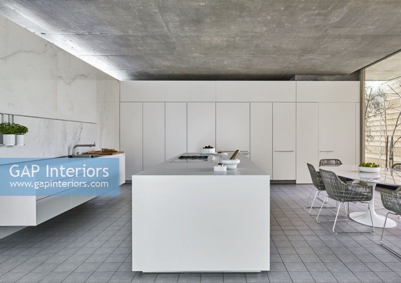 Contemporary kitchen diner with white furniture and concrete floor