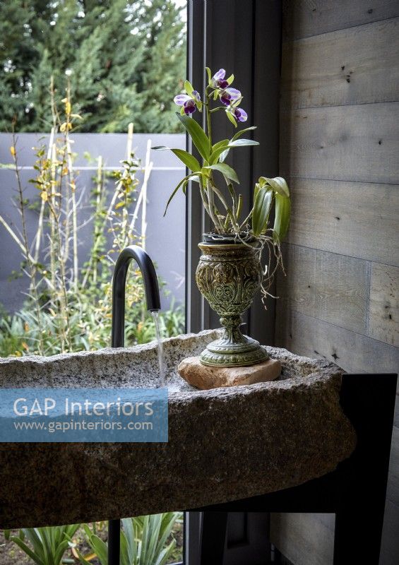 Plant in urn in unusual stone sink next to window