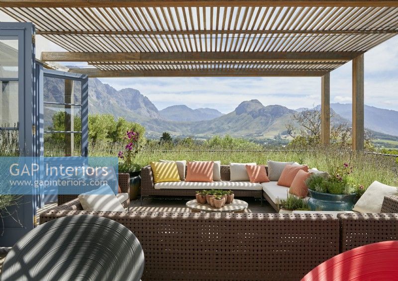 Wooden pergola above outdoor seating area with views of mountains