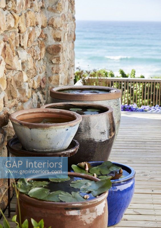 Collection of large pots on decking with sea views 