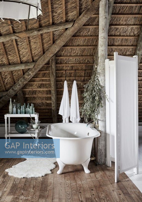 Freestanding bath in country bathroom with straw ceiling