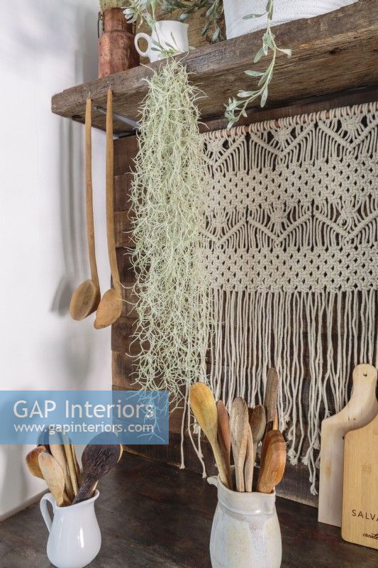 A macramÃ© hanging is unexpected and flirty as a backdrop to workaday kitchen tools.